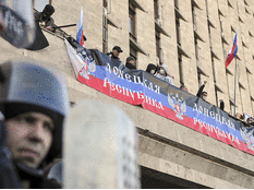 Pro-Russian protesters stand behind a banner as they storm the regional government building in Donetsk